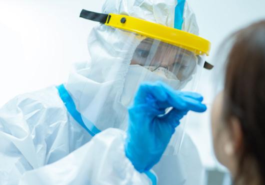 Person in full PPE obtaining a nasal swab from a patient 