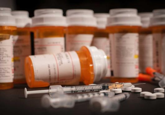 Photo of opioid pill bottles and a syringe