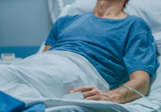 The torso of a patient lying in a hospital bed