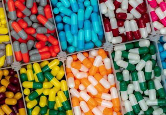 Multiple rectangular compartments filled with large, multi-colored pills