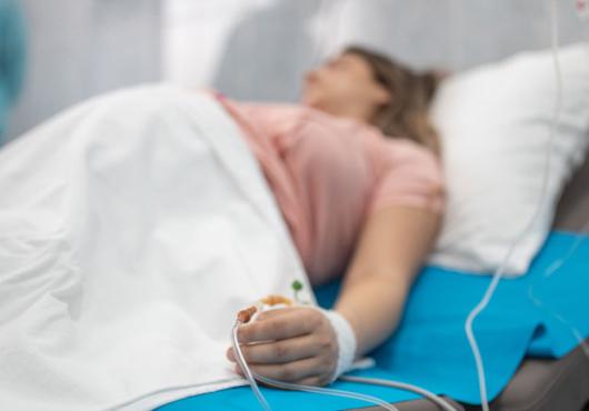 Out of focus image of a pregnant woman on a hospital bed with IV 
