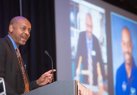 Satcher speaking at a podium at the Spotlight dinner
