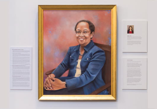 Oil painting of Higginbotham flanked by placards with the artist's bio, Q&A with her, and info about the artwork