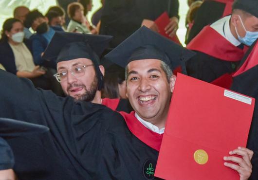 Photo of master's student smiling and holding diploma