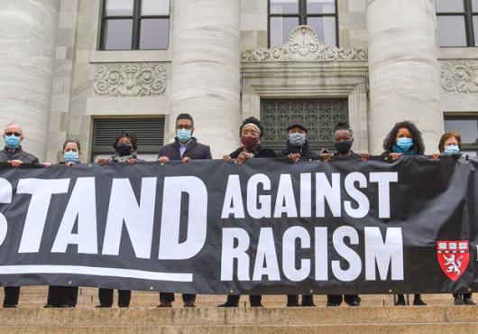 HMS community members holding a 'Stand Against RAcism' banner 