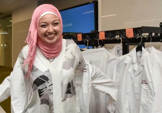 HMS Class of 2022 medical student donning her white coat. 