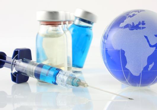 Image of syringe, 2 vaccine vials and a small Earth globe