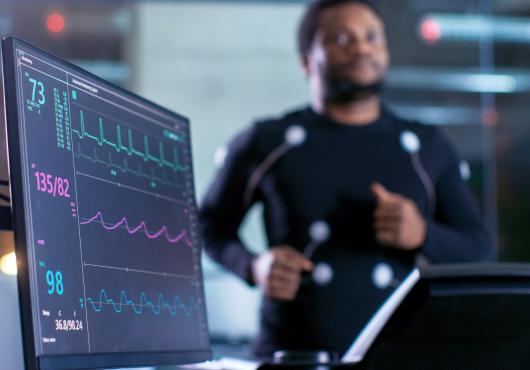 Blurred image of a man on a treadmill with electrodes attached and connected to a heart monitor in a research lab
