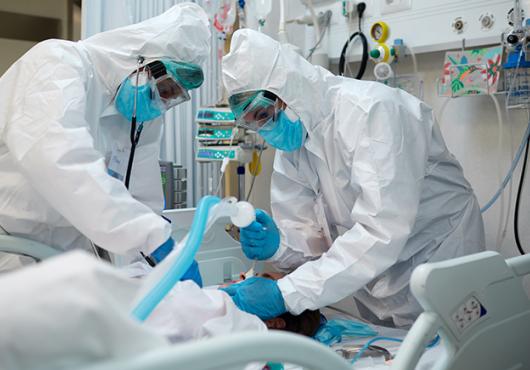 two health care workers intubating a patient with covid-19