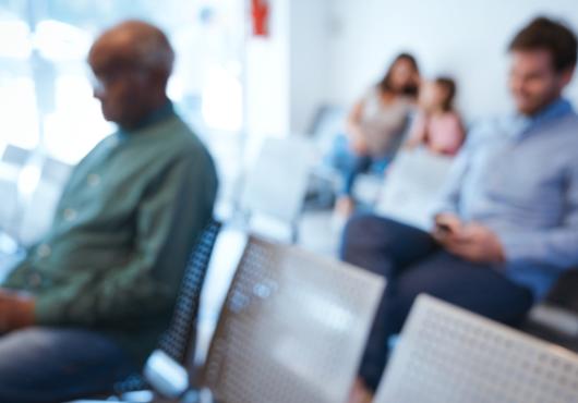 A blurry image of people in a waiting room.