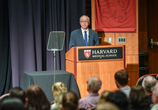 A person standing at a podium with a crowd of people watching
