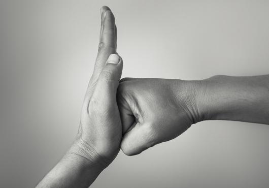 Black and white photograph of one hand stopping another hand from punching