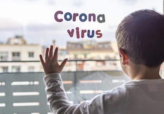 Child silhouetted against hospital window with letter-shaped magnets spelling out Corona virus