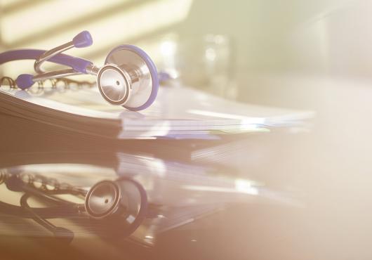 Photograph with soft filter; a stethoscope on a desk with a reflection on the desktop, no doctor there