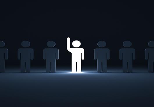 One glowing light man raising his hand among other dim people in the row on dark blue background with shadows