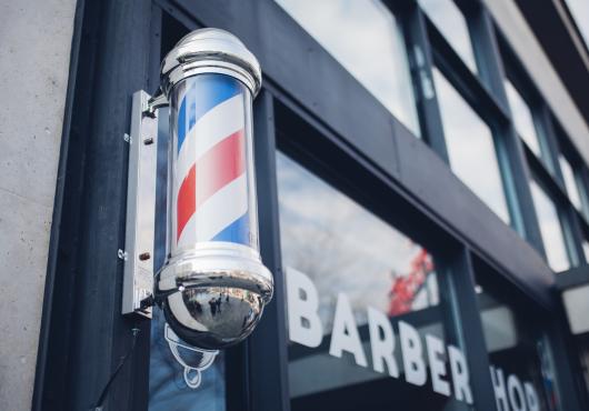Photo of striped barbershop pole mounted on door of shop