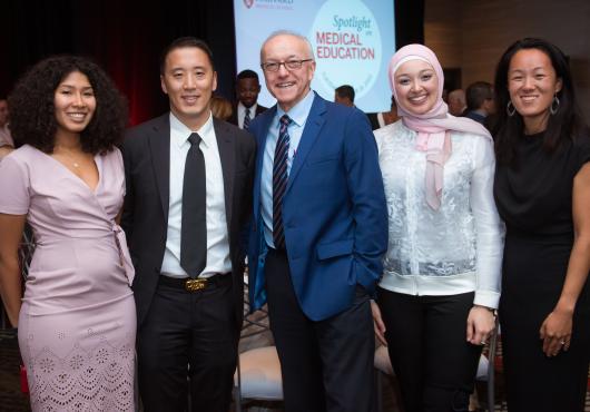 Photo of 4 students and former student with Dean Daley, all smiling at the camera