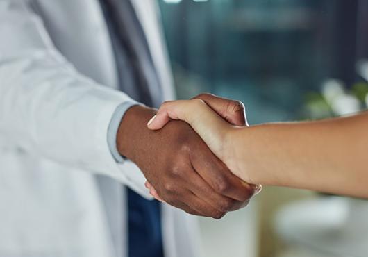 Doctor in a white coat shaking a patient's hand 