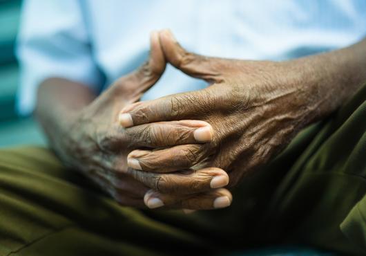Closeup of hands of elderly Black man sitting on bench