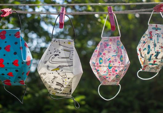 Diverse, colorful masks hang on a laundry line.