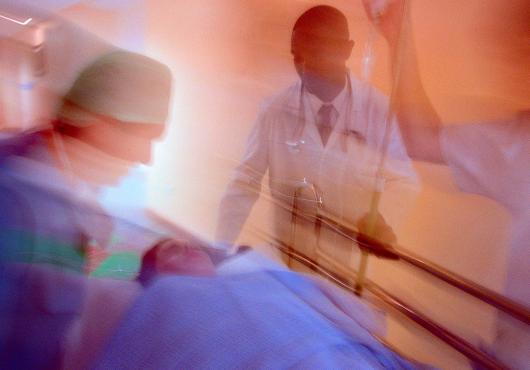 Motion blurred photo of hospital staff wheeling a patient on a gurney down a corridor