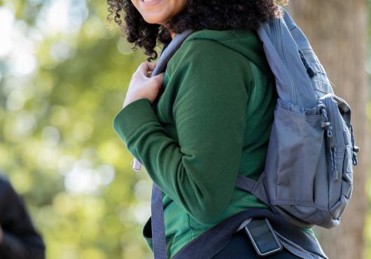 Young woman outdoors with backpack wearing a glucose monitor