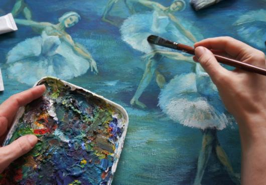 Close-up of a painter's hands working on a picture of dancers.