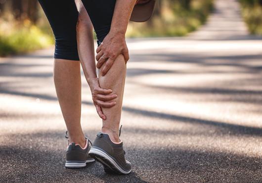 Person grasping lower leg in pain