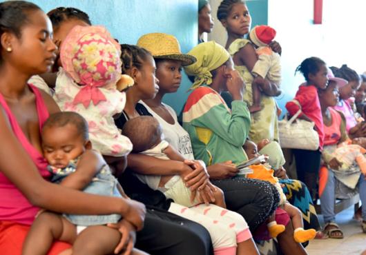 Women and children sitting and standing in a waiting room.