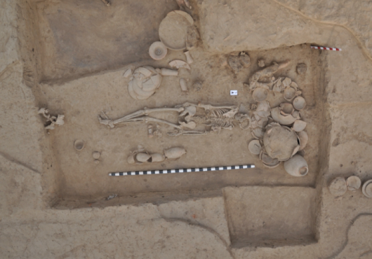 Photo of gravesite taken from above shows a skeleton and pots with a measuring stick