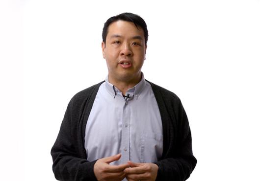 Young Asian man in a button-down shirt and vest, gestures