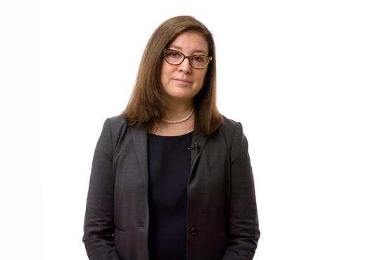 Brunette woman in a blazer holding her hands together in front