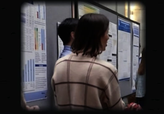 screen grab of video showing a person in front of a poster