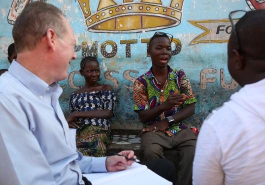 Four people having a conversation sit in front of a colorful mural