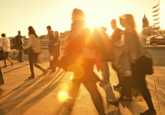 Motion blurred photo of people walking backlit by the sun.