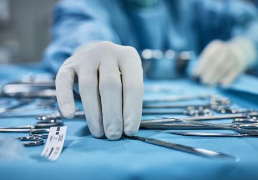 Hands reaching for surgical tools.