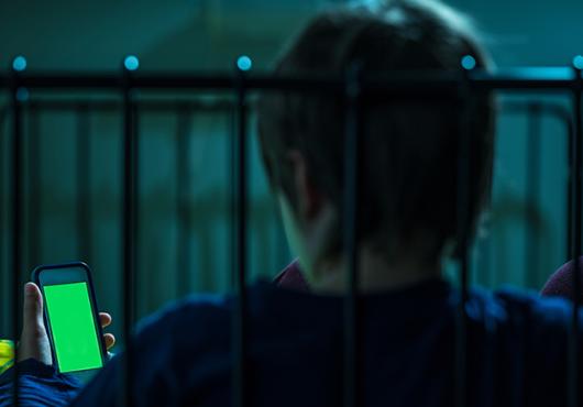 Teen looking at screen in bed at night