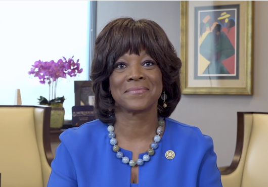 Image of Dr. Rice, wearing a blue suit, seated at a desk in her office