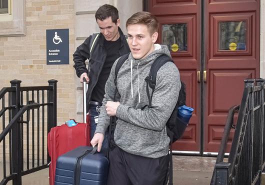 photo of two male students carrying luggage down stairs in front of Vanderbilt Hall