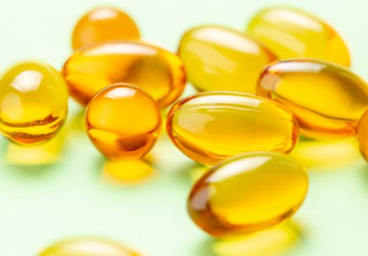 photo of vitamin D capsules on a light green background