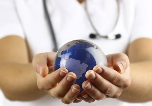 Stock image of white coated person holding a small earth globe