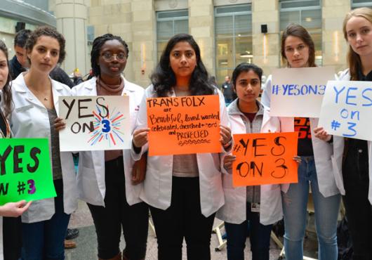 HMS students in white coats holding rally posters