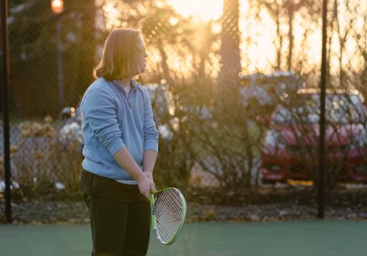 Silhouette of a male teen with Down syndrome holding a tennis racket