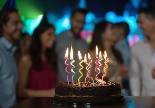Close-up on a candle-lit cake on a table at a birthday party 