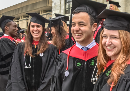 Smiling group of graduates on the steps of the Quad