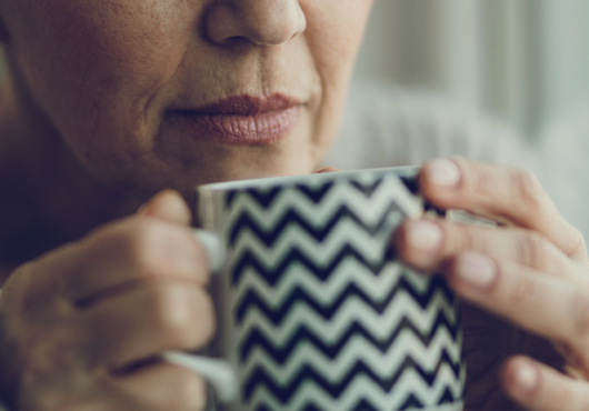close up of older woman holding coffee mug to her nose