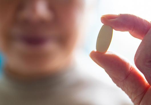 blurred face of senior women showing a pill