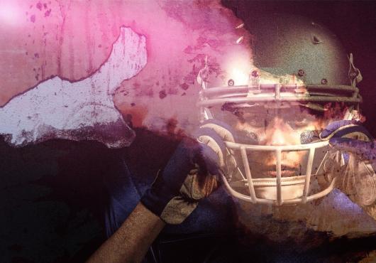 A headshot of a football player gripping their helmet 