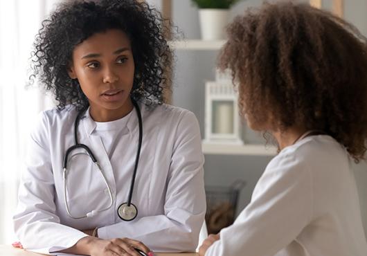Young Black doctor has serious conversation with pediatric patient of color