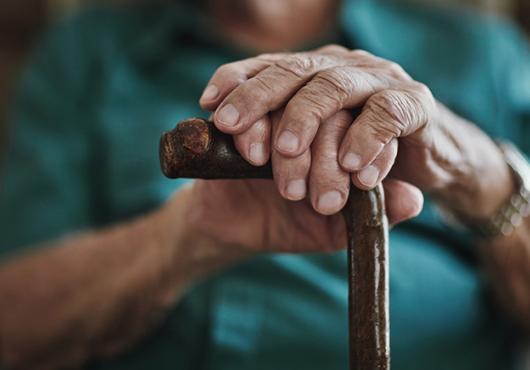 close up photo of a senior man's hands on a cane